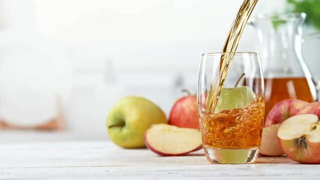 Super slow motion of pouring apple juice into glass. Placed on white table with kitchen interior. Filmed on high speed cinema camera, 1000 fps.