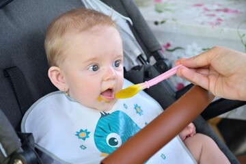 Mom serves baby food porridge to the toddler