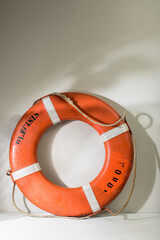 Red orange sea life preserver against a gray wall