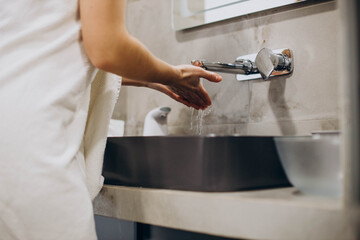 Woman washing hands in bathroom sink