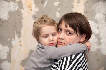 Frightened children   standing against   wall huddled together