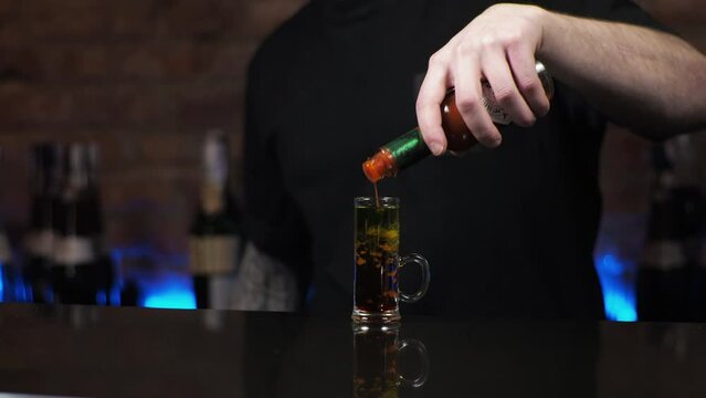 Bartender is a young man The guy pours drinks, prepares alcoholic shots black cuttlefish in the bar