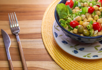 chickpeas with leaves, olives and tomatoes in a blue bowl on the table