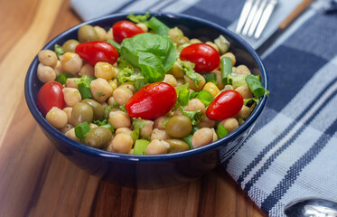  chickpeas with leaves, olives and tomatoes in a blue bowl on the table