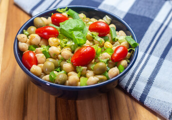 chickpeas with leaves, olives and tomatoes in a blue bowl on the table