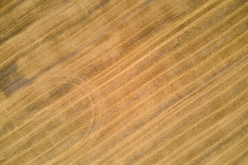 Aerial landscape view of yellow cultivated agricultural field with dry straw of cut down wheat after harvesting
