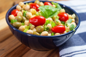 chickpeas with leaves, olives and tomatoes in a blue bowl on the table