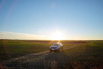 Obraz na płótnie Canvas Aerial view of car driving on dirt road at sunset. Traveling by vehicle concept