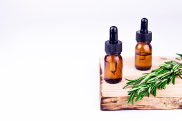 Aromatherapy herbal oil. Bottle glass with rosemary essential oil and fresh rosemary twig on white background.