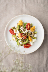Healthy egg and avocado salad. Salad for breakfast with tomato, avocado, feta, pine nuts, sesame, flax seeds and boiled egg on a concrete background