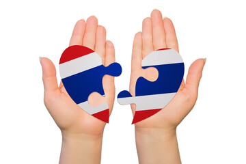 Woman hands are holding two parts of puzzle heart. National concept on white background. Thailand