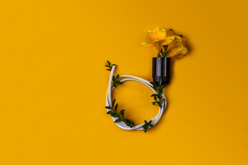 Electric cartridge with electric wire with flowers and leaves on a yellow background with copy space.