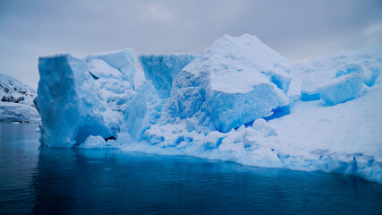 Fototapeta na wymiar Icebergs in the oceans near Paradise Bay on an overcast day with dark mood in Antarctica.
