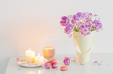 bouquet of pink spring flowers and burning candles on  white table