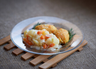 Vegetable stew with meatballs on a transparent plate on a canvas tablecloth