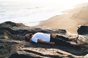 Caucasian male lying on black mat feeling enlightenment calmness and mindfulness appeasement during...