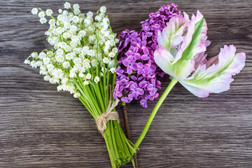 Lily of the valley ,tulip and purple lilac on a  wooden background. Spring flowers background 