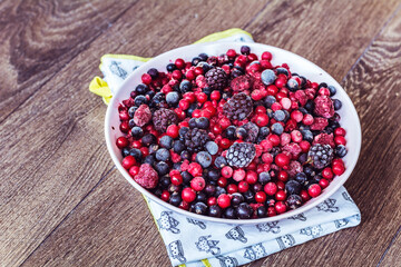 Frozen Forest Fruits in Bowl on a Wooden Background