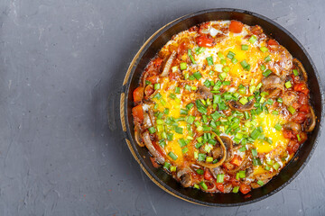 Shakshuka with herbs in a frying pan on a gray background.copy space.