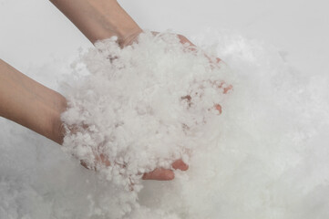 Fototapeta premium Holofiber. Natural filler for pillows and blankets in female hands