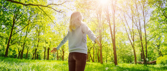 Woman standing in the spring natural park with wide openning hands.
