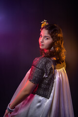 Mexican teenager with an embroidered dress and multicolored lights, long curly hair with a rebozo on a black background, with a beautiful smile