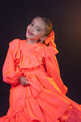 mexican girl with orange traditional costume dancing with a beautiful smile and braids on black background