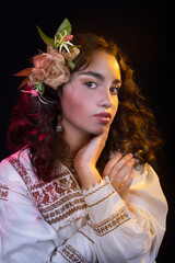 Mexican teenager with an embroidered dress and multicolored lights, long curly hair with a rebozo on a black background, with a beautiful smile