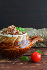 Delicious buckwheat in a pot on a wooden background.