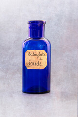 ancient apothecary blue jar with a label where it is written "salicylate de Soude" in french for medicine. the pot is isolated over white background. translation : sodium salicylate