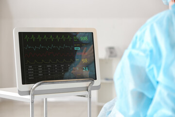 Doctor near modern heart rate monitor in operating room