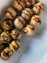 Baked sushi rolls japanese food. Hot salmon, tuna and unagi rice and nori dish. Sushi tasty meal with sauce on top close up view 