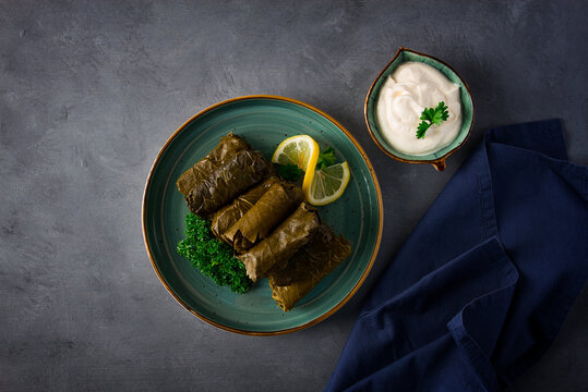 Dolma, cabbage rolls, grape leaves with filling, white sauce, lemon and herbs, rustic, selective focus, no people,