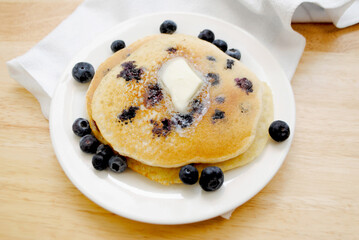 Eating Blueberry Pancakes Covered with Butter	