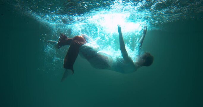 Depression and burnout. Young beautiful woman with eyes closed dives, slowly sinks down helpless under water slow motion