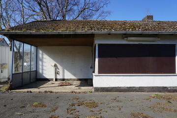 Altes verlassenes geschlossenes Bahnhofhaus vor Baum und blauem Himmel bei Sonne im Winter