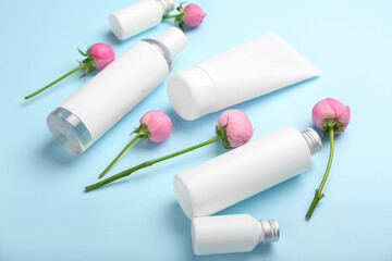 Different cosmetic products and beautiful rose flowers on blue background
