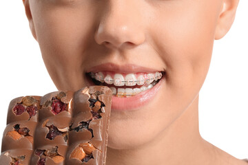 Pretty teenage girl with dental braces and chocolate on white background, closeup