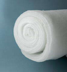 A roll of padding polyester on a blue background. Large skein of synthetic winterizer
