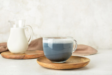 Wooden plate with glass cup of delicious Charcoal Latte on light background