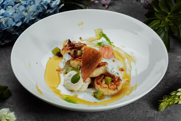 An ideal breakfast. Cottage cheese pancakes with caramel, almonds and cream sauce in a white plate. Ukrainian syrniki