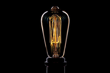 Oblong original incandescent light bulb with lit filament on white background in art studio photo 