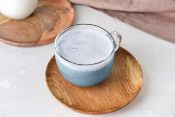 Wooden plate with glass cup of delicious Charcoal Latte on light table