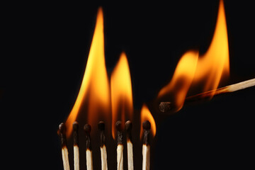 Lighted match next to row of burning matches on black background. Inspiration concept