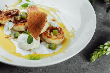 An ideal breakfast. Cottage cheese pancakes with caramel, almonds and cream sauce in a white plate. Ukrainian syrniki
