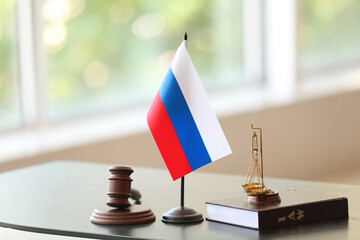 Judge gavel, scales, notebook and Russian flag on dark table in office