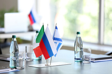 Flags of Italy, Israel and Russia on table in conference room