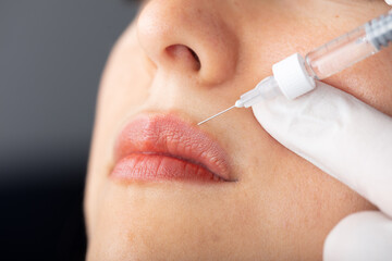 Young lady getting injections for bigger, fuller lips. The woman in the beauty salon. Plastic surgery clinic.
