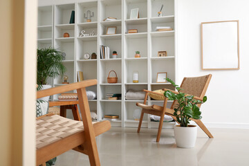 Interior of light living room with big shelving unit and armchairs