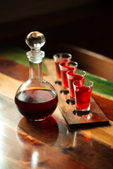 Obraz na płótnie Canvas Decanter with red berry liqueur and shot glasses on the table